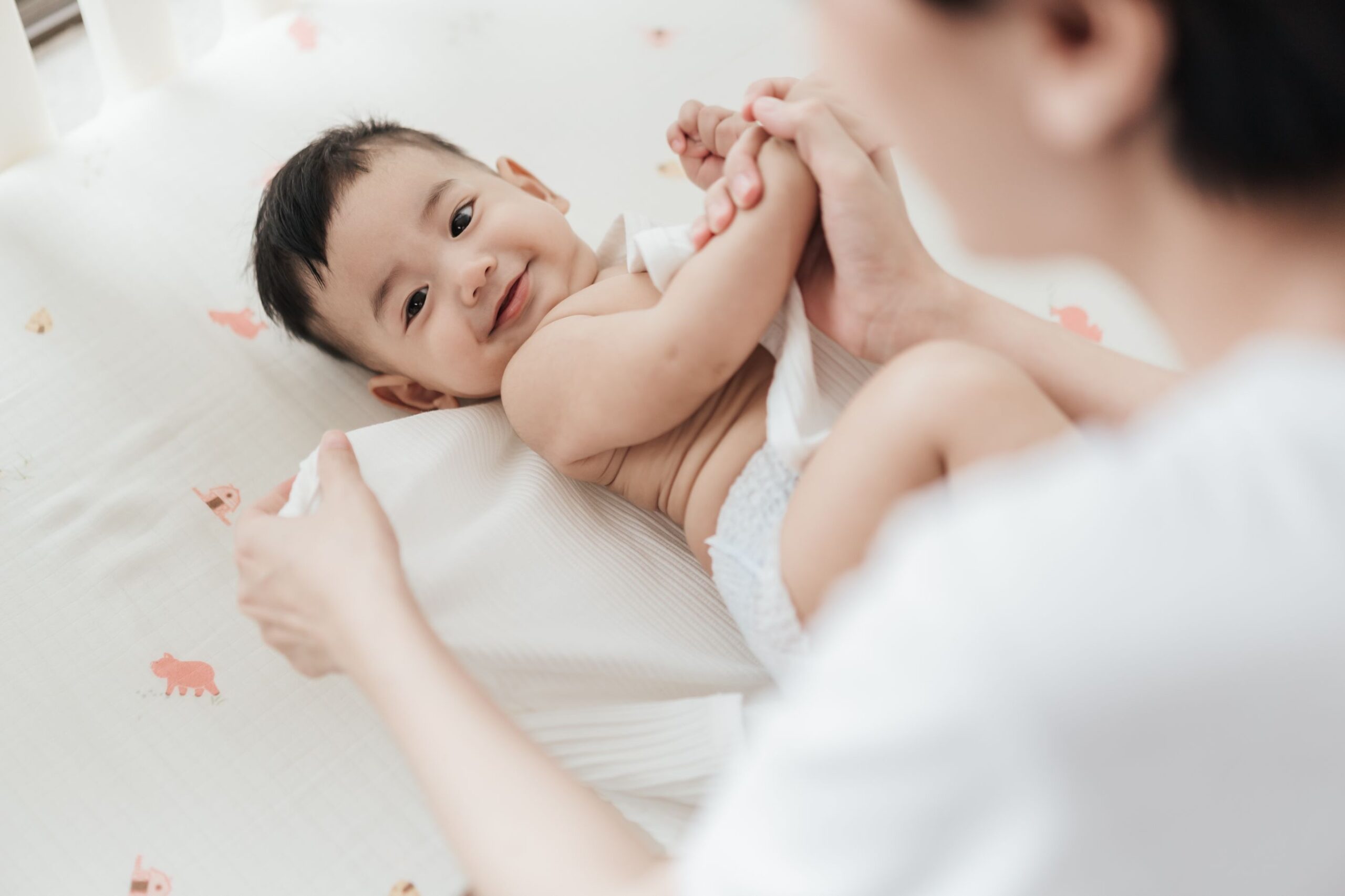 คุณแม่กำลังเปลี่ยนผ้าอ้อม ซึ่งเป็นของใช้จำเป็นสำหรับเด็กอ่อน